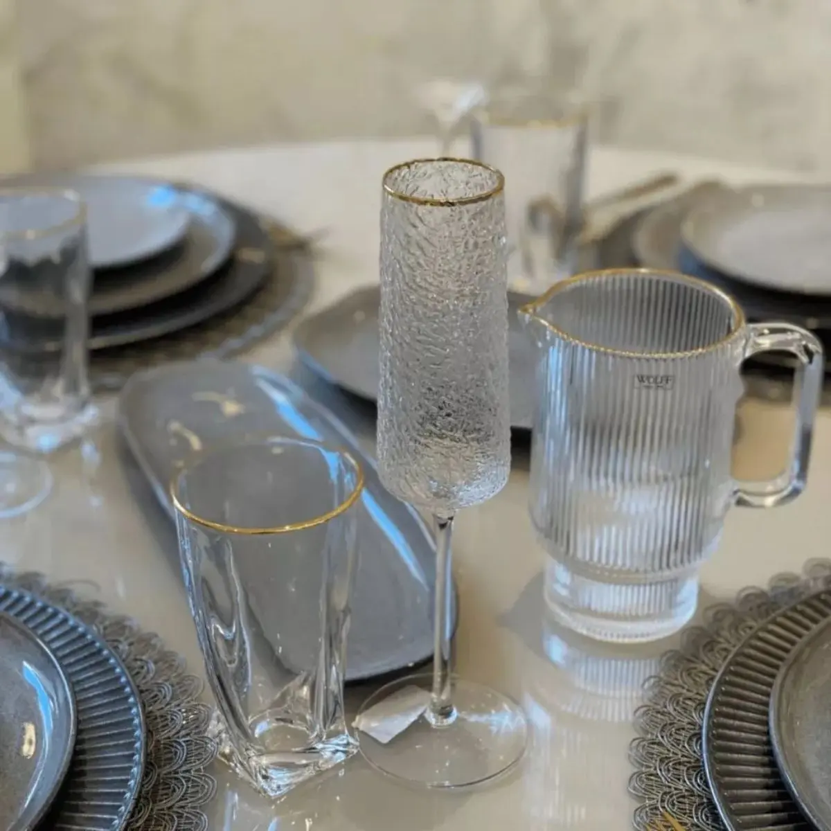taça de champanhe lyor martelado em mesa posta com outros itens de vidro como jarras